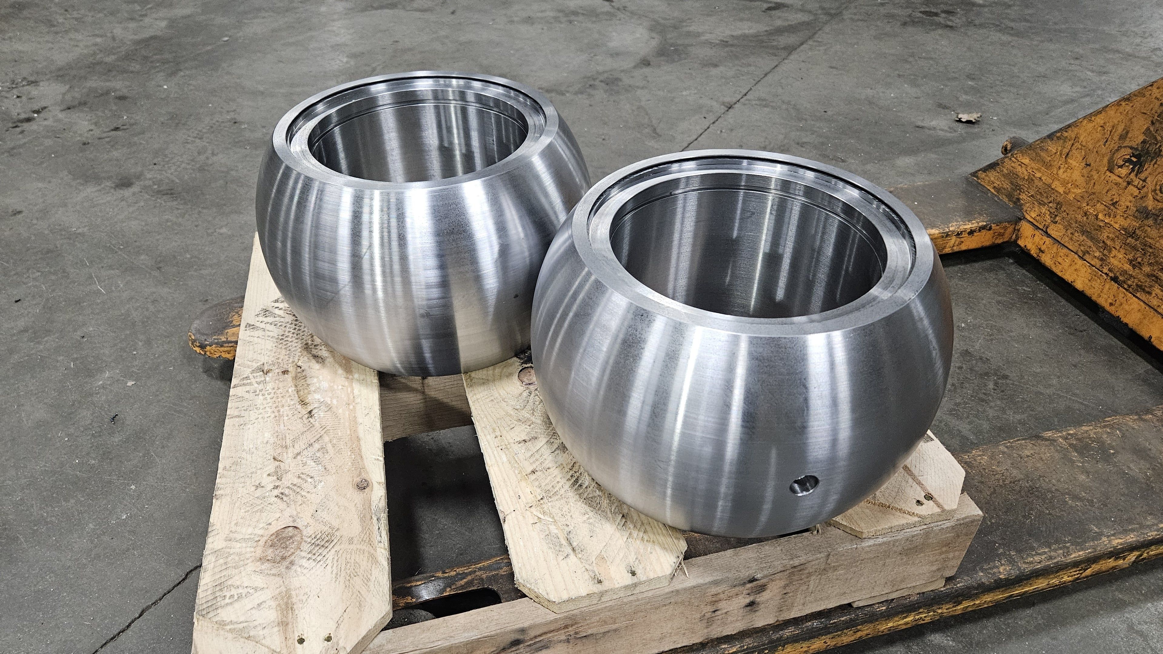 Two large hemispherical steel forgings machined smooth on a shop pallet