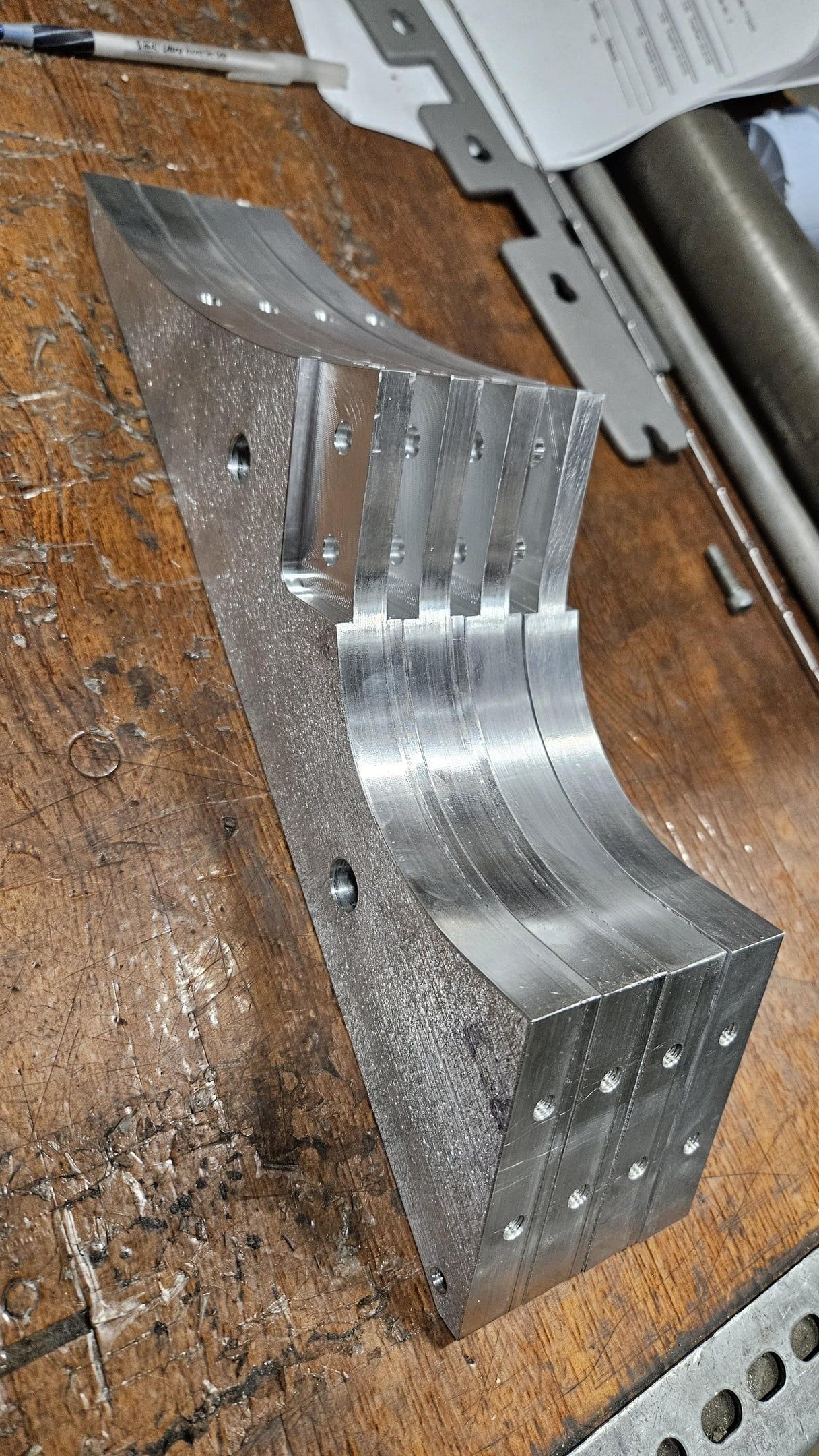 Curved aluminum bracket with machined cooling fins and drilled mounting holes