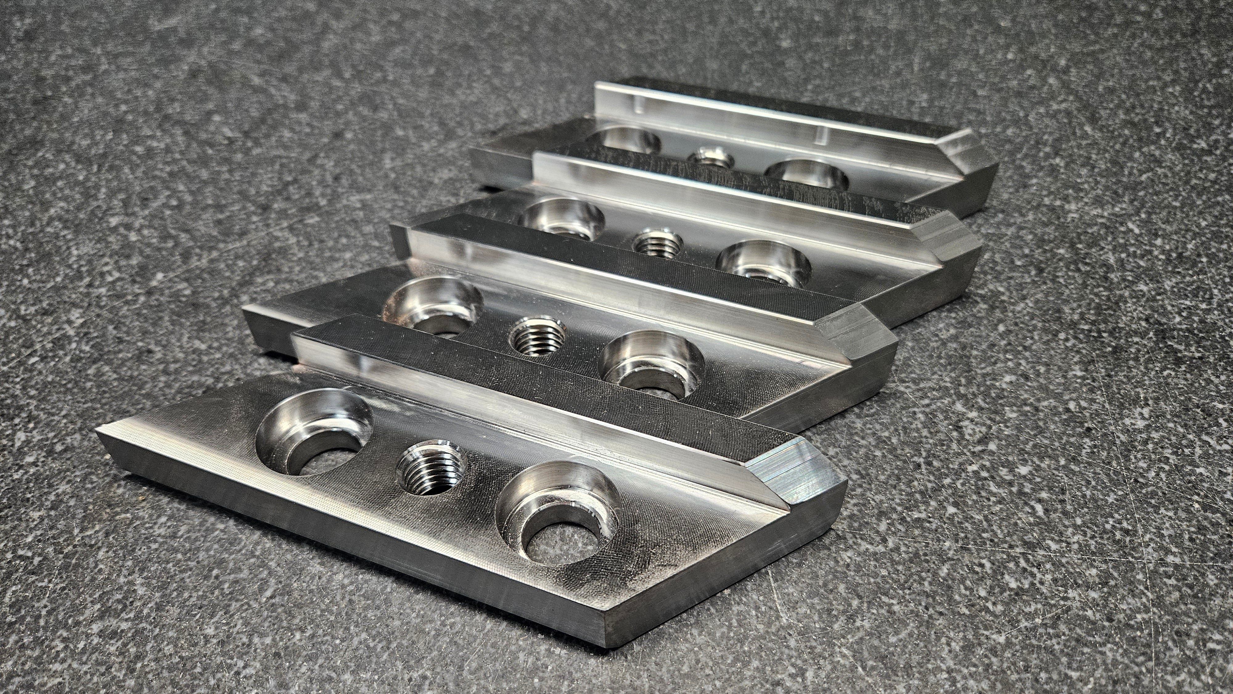 Stack of machined aluminum tooling plates with counterbored mounting holes