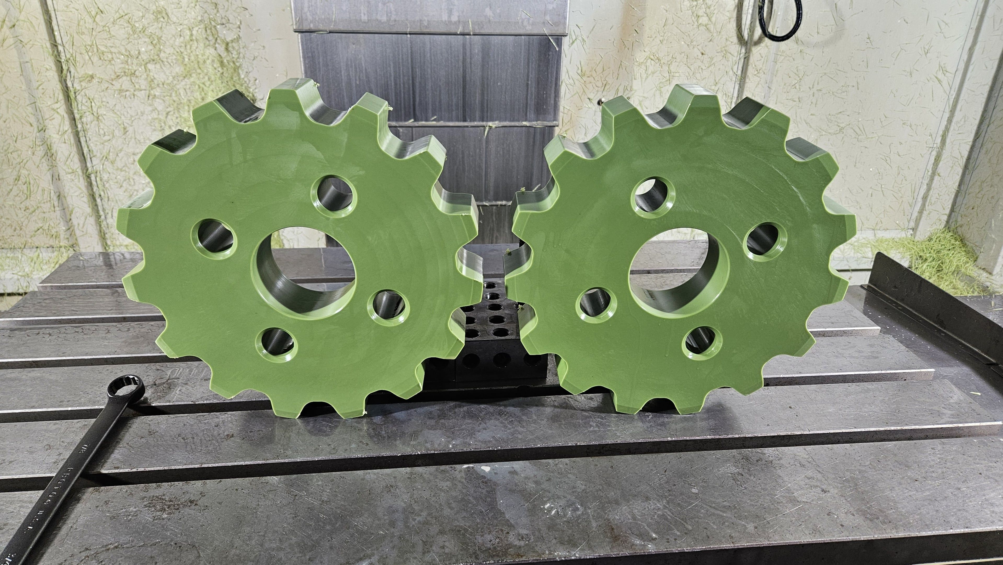 Pair of green powder-coated sprocket gears with drilled bolt holes
