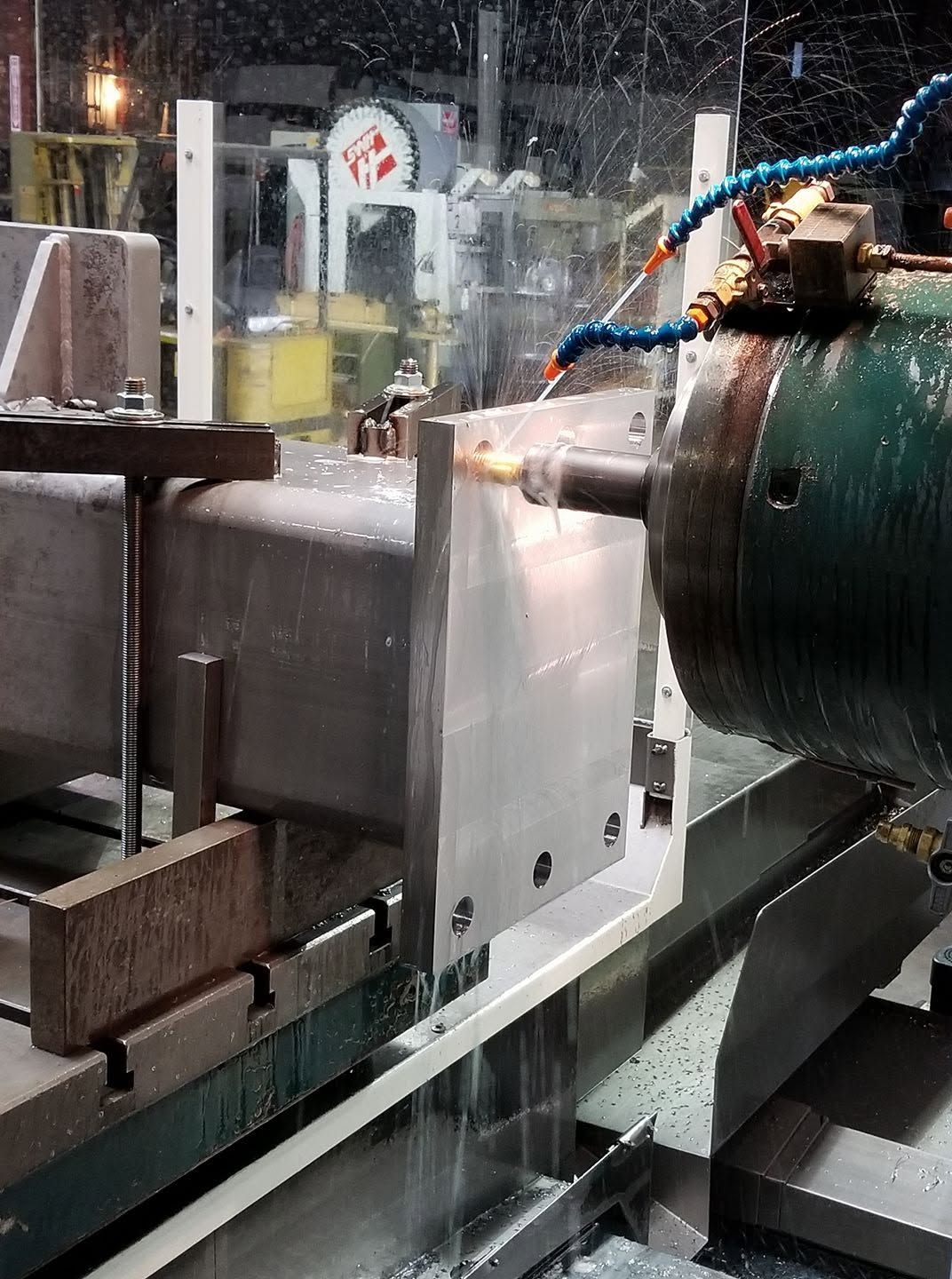 Steel cylinder being turned on a large boring mill with coolant spray